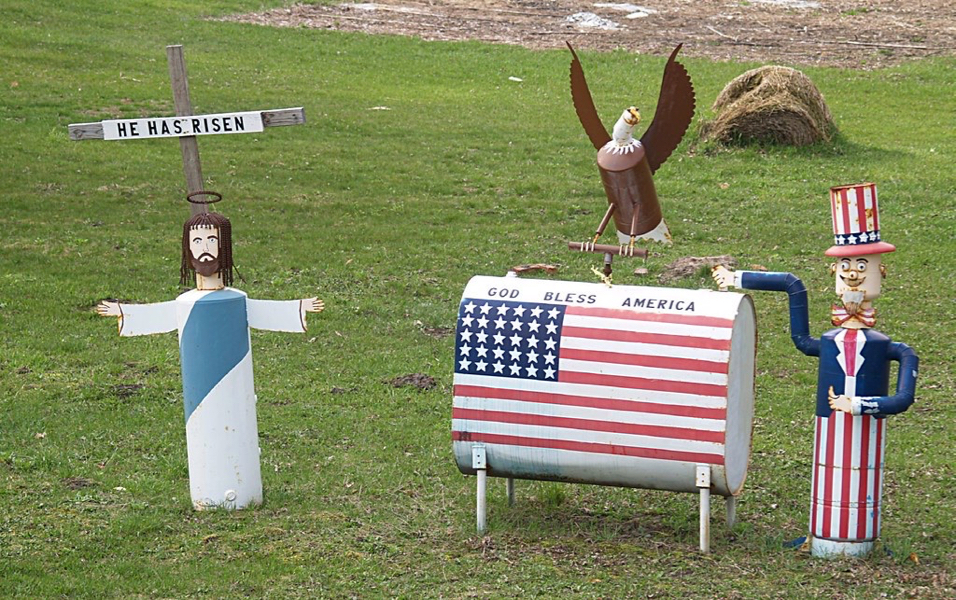 "'He Has Risen' & 'God Bless America' Lawn Ornaments, On Route 31 (Just North Of Beulah, MI)" by takomabibelot is licensed under CC BY 2.0